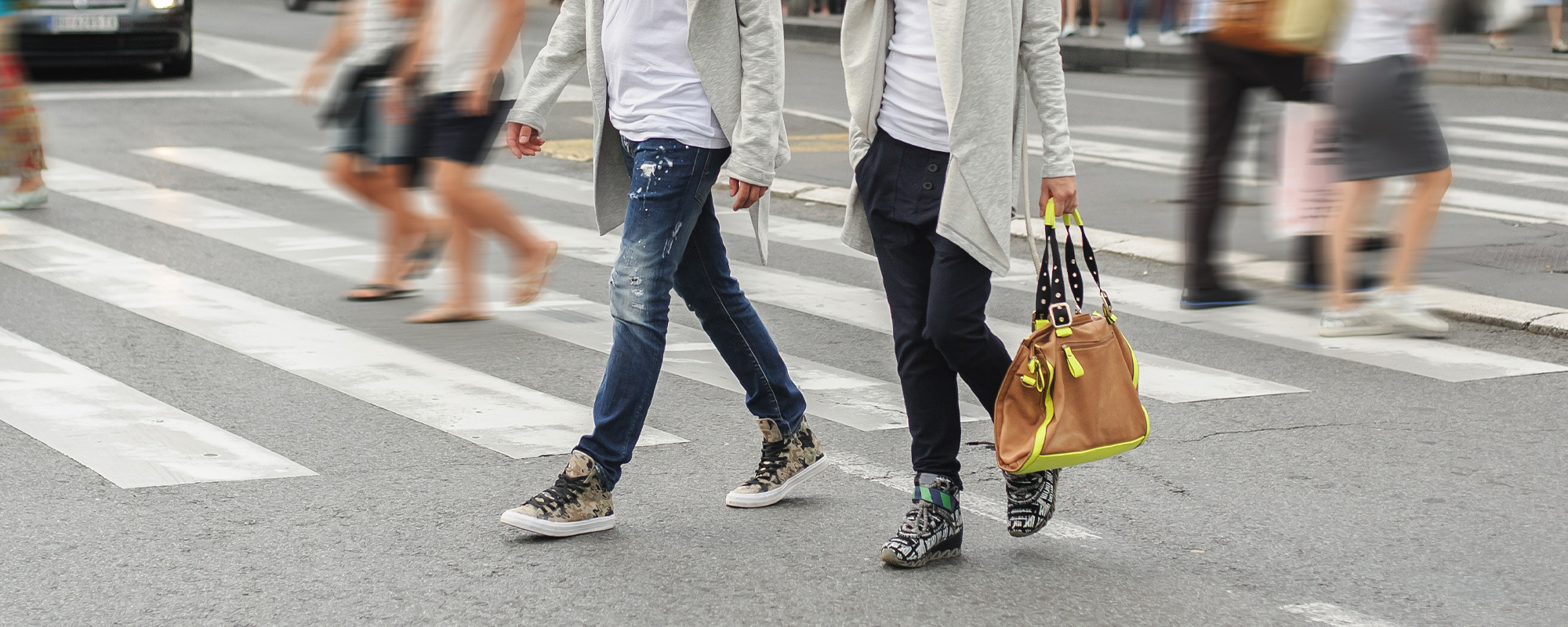 fashionable couple crossing road at pedestrian zebra crossing