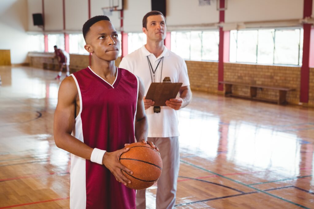 boy holding basketball coach behind him