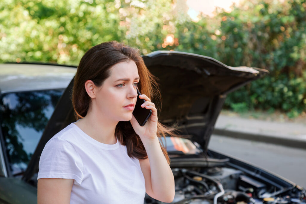 woman on phone standing in front of car