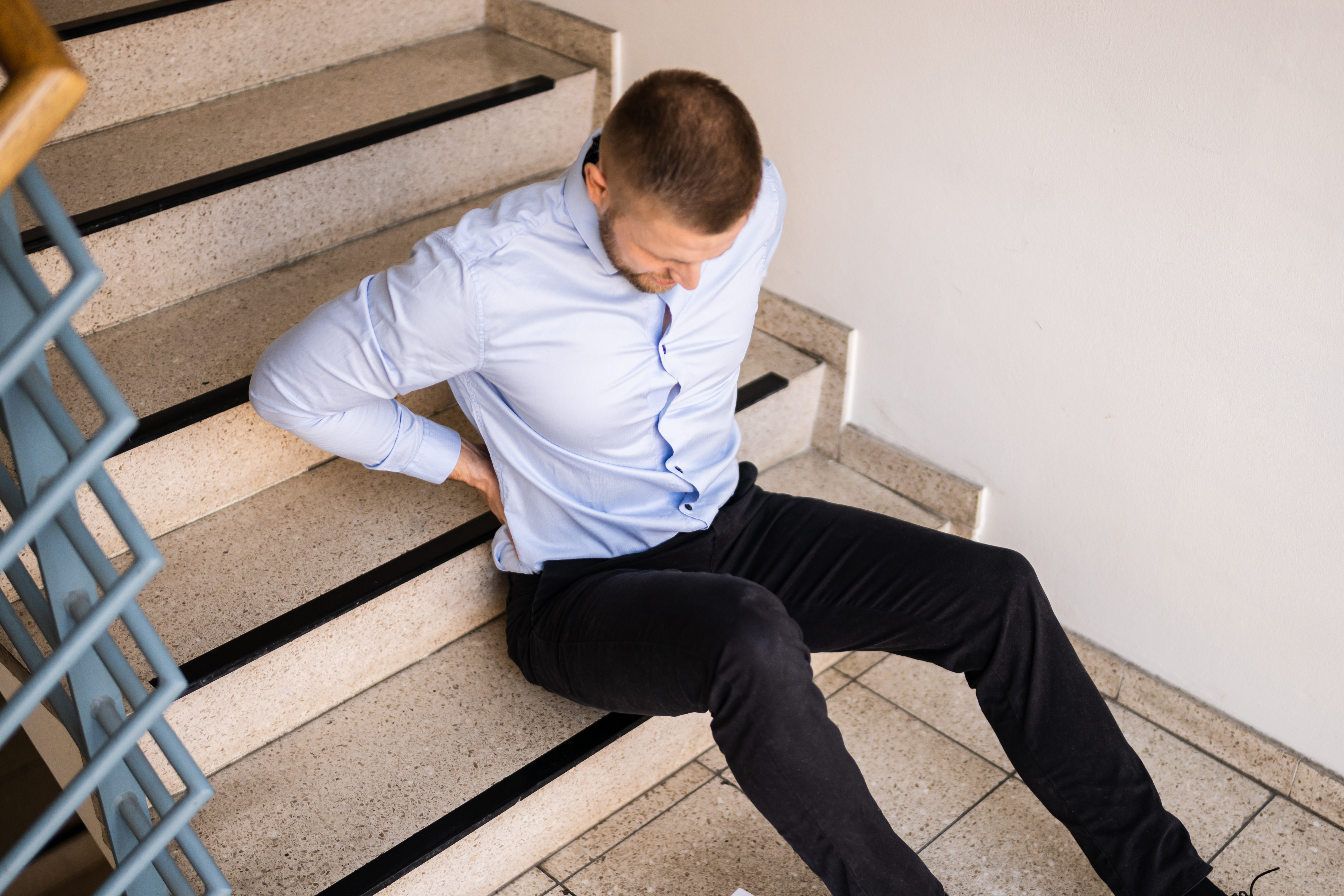 man on staircase holding his back
