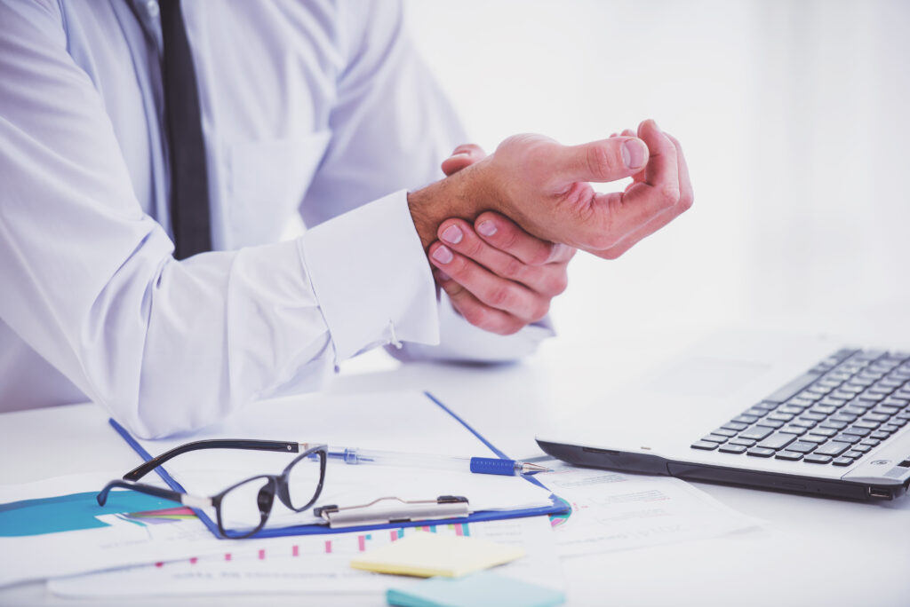 man holding his wrist while working in office