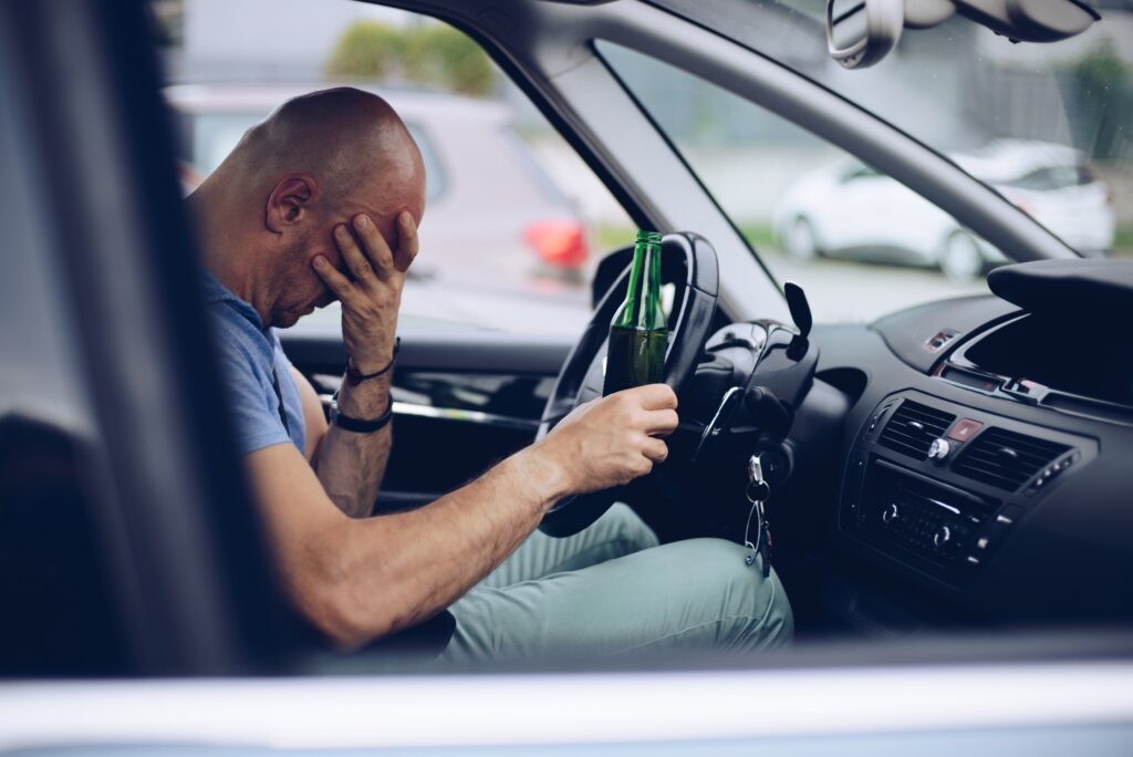 Drunk driver drinking alcohol in car and holding beer