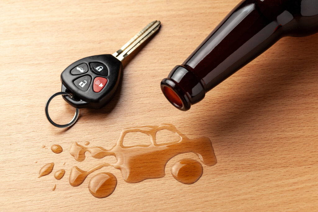 Drunk driving. Accident with a broken car from alcohol. Beer bottle and car keys. Broken car